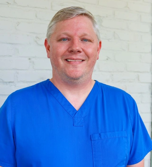 Professional headshot of Dr. Josh Girod smiling in royal blue scrubs.