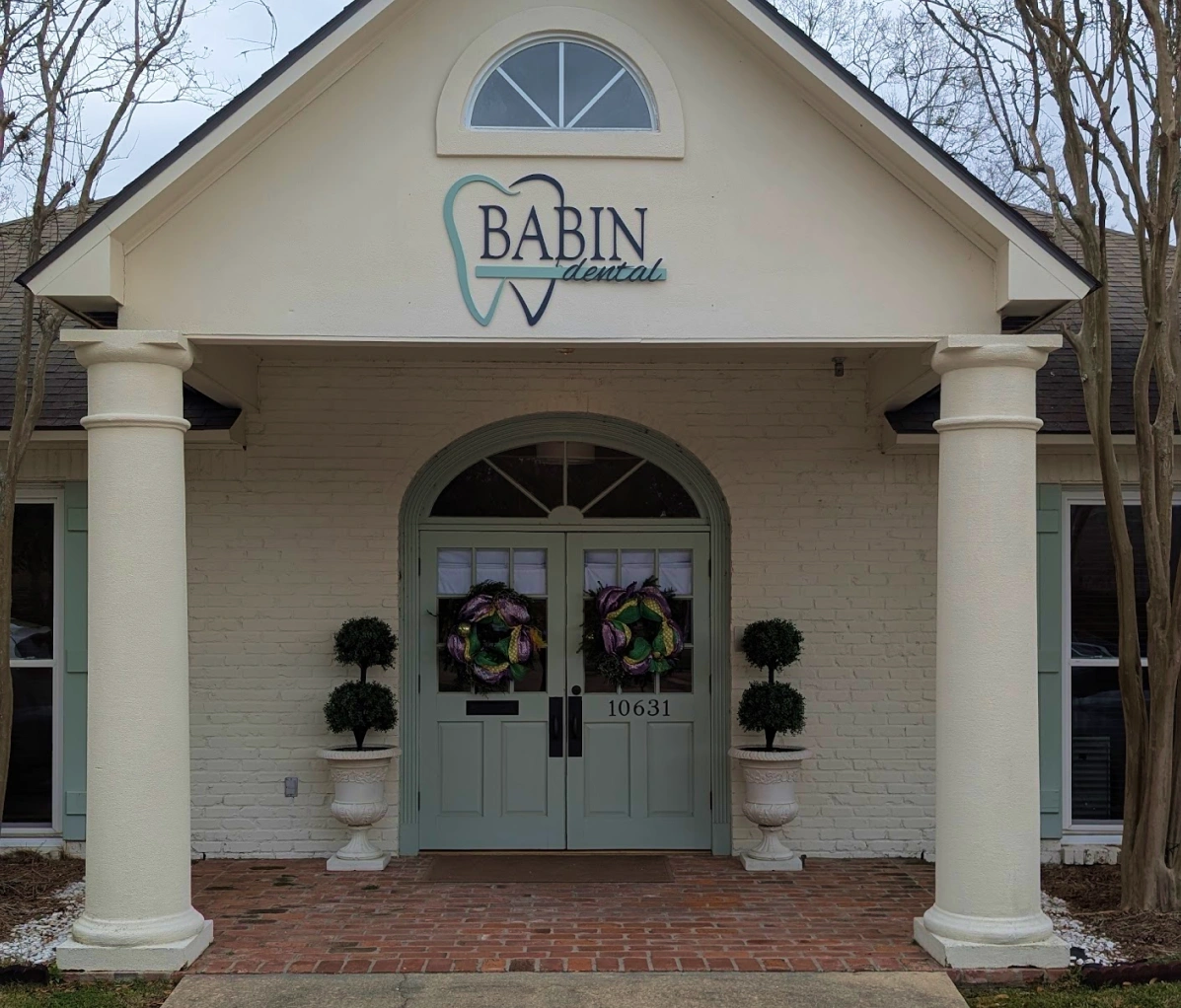 Front entrance of Babin Dental featuring white columns and decorative door wreaths.