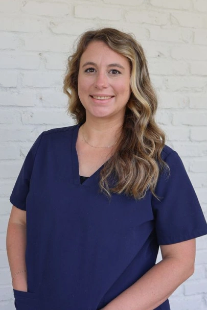 Professional headshot of Hannah smiling in dark navy blue scrubs.